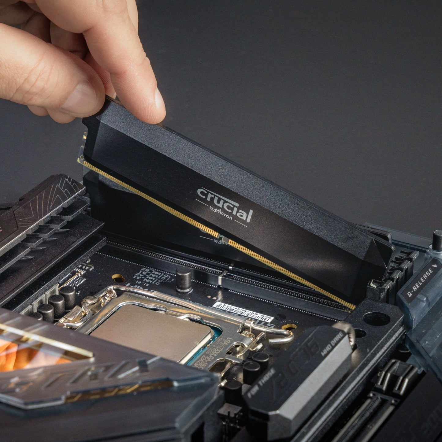 Hand inserting a Crucial RAM stick into a motherboard