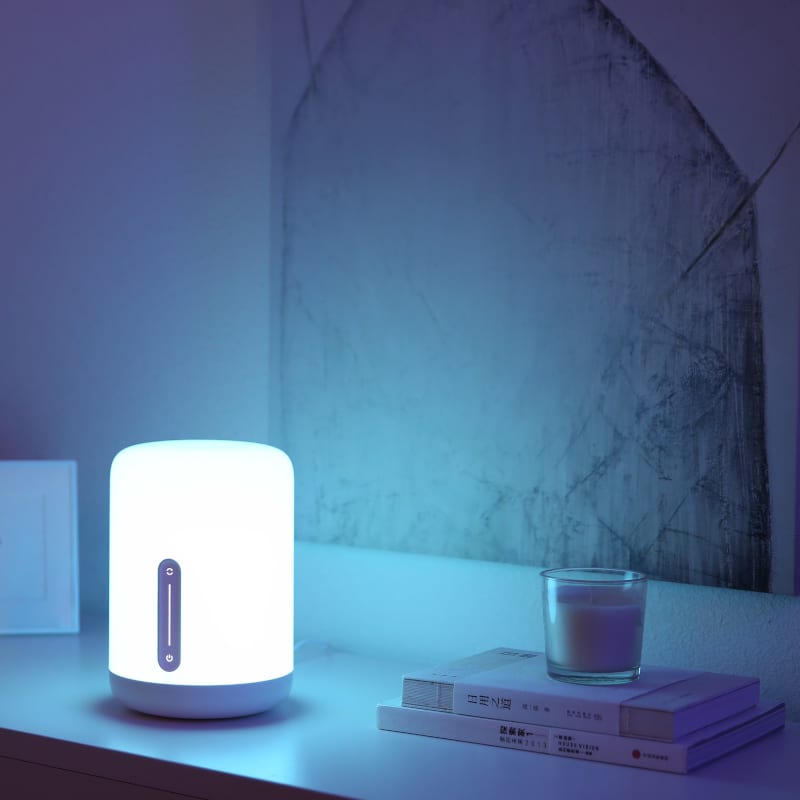 Smart lamp on a shelf with books and a glass of milk in a dimly lit room