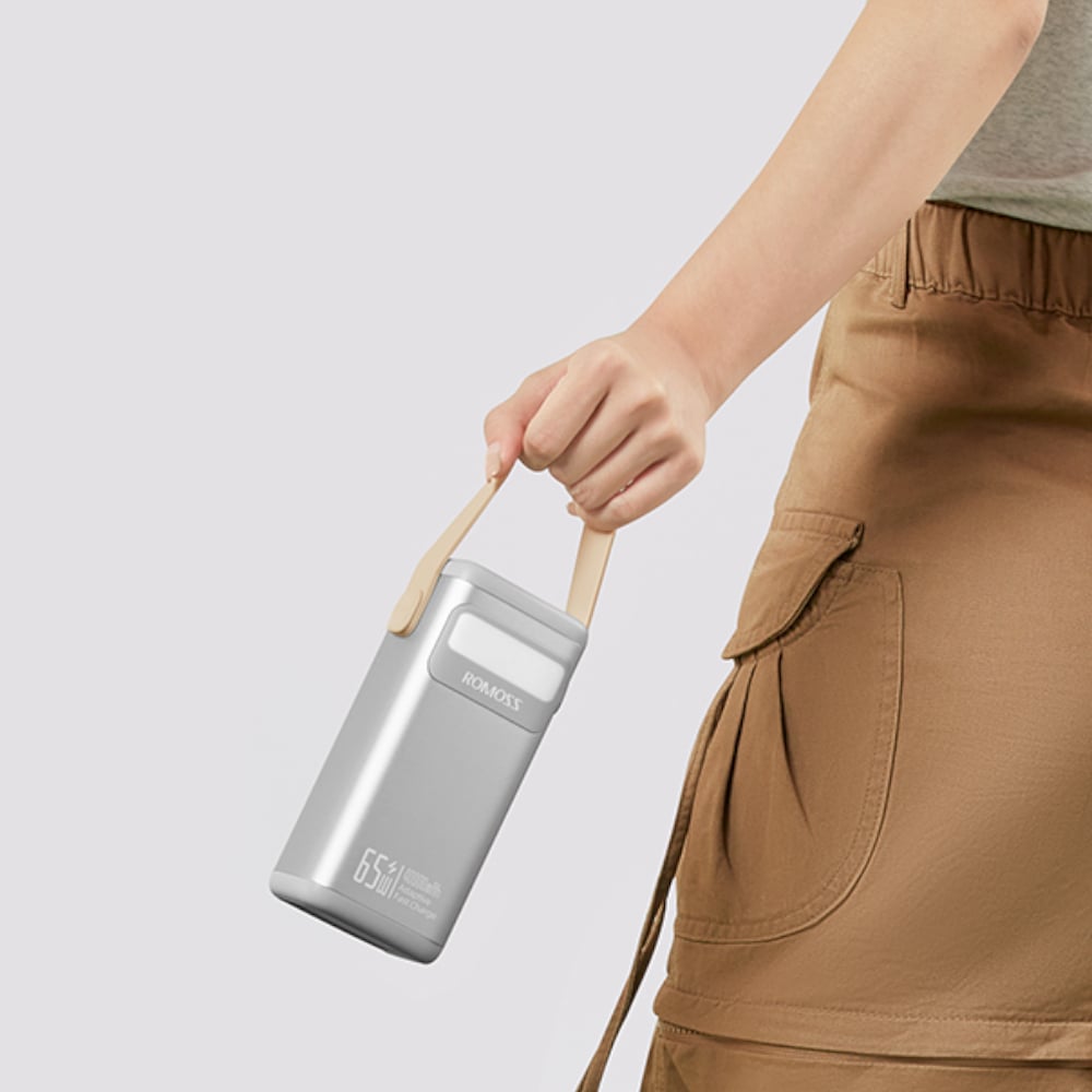 Person holding silver power bank with handle against a light gray background
