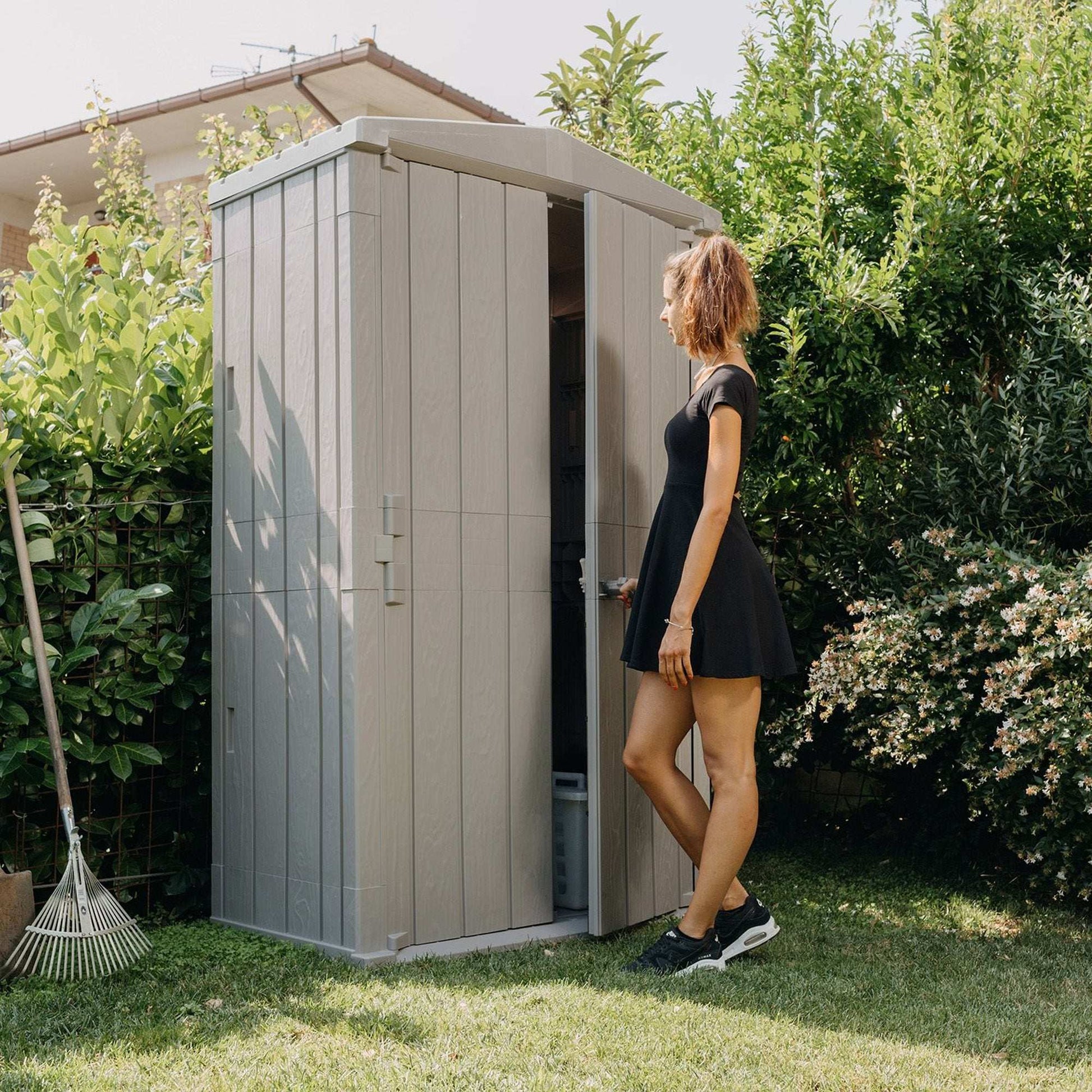 Woman standing next to a garden shed in a backyard setting