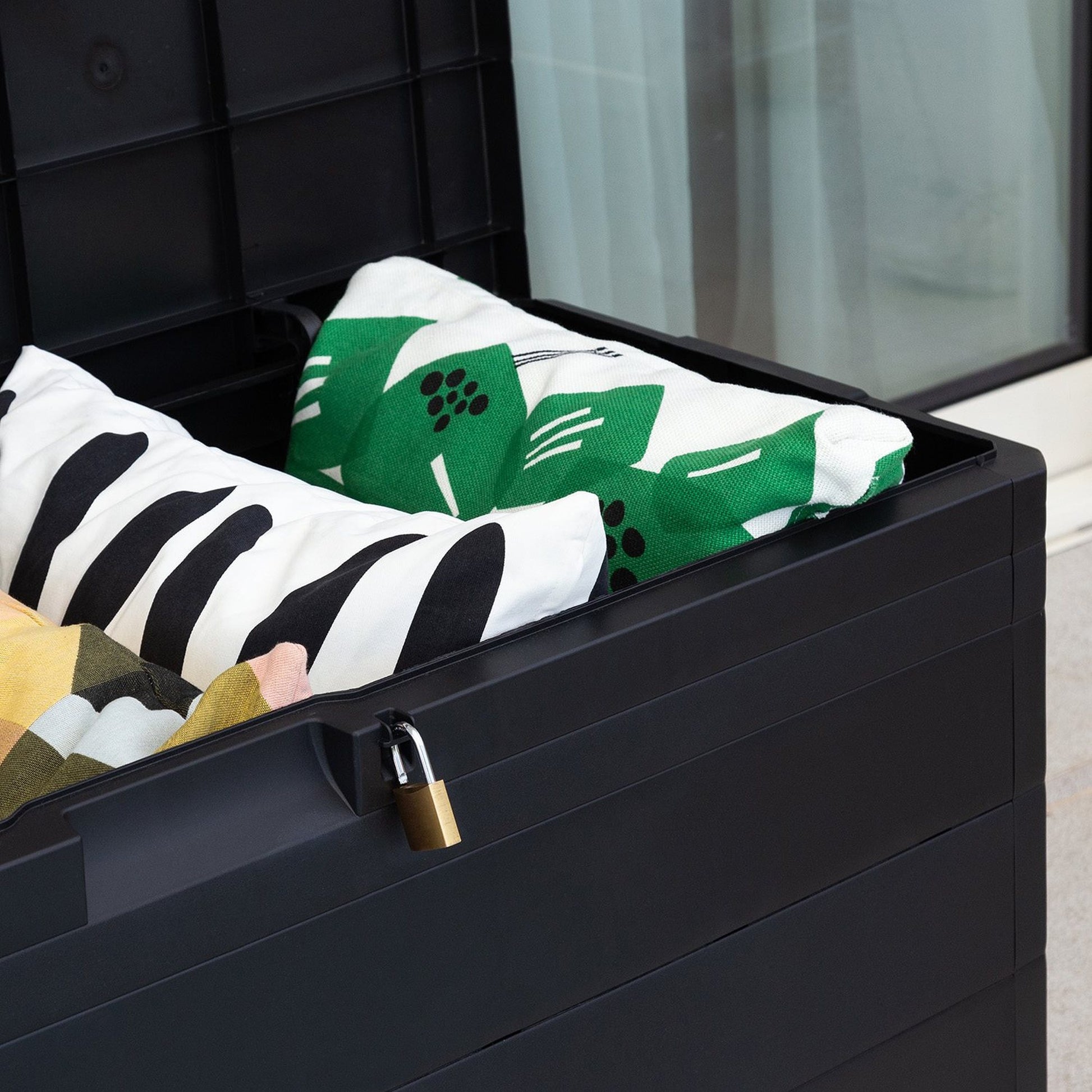 Black storage box with colorful pillows and a lock on a neutral background