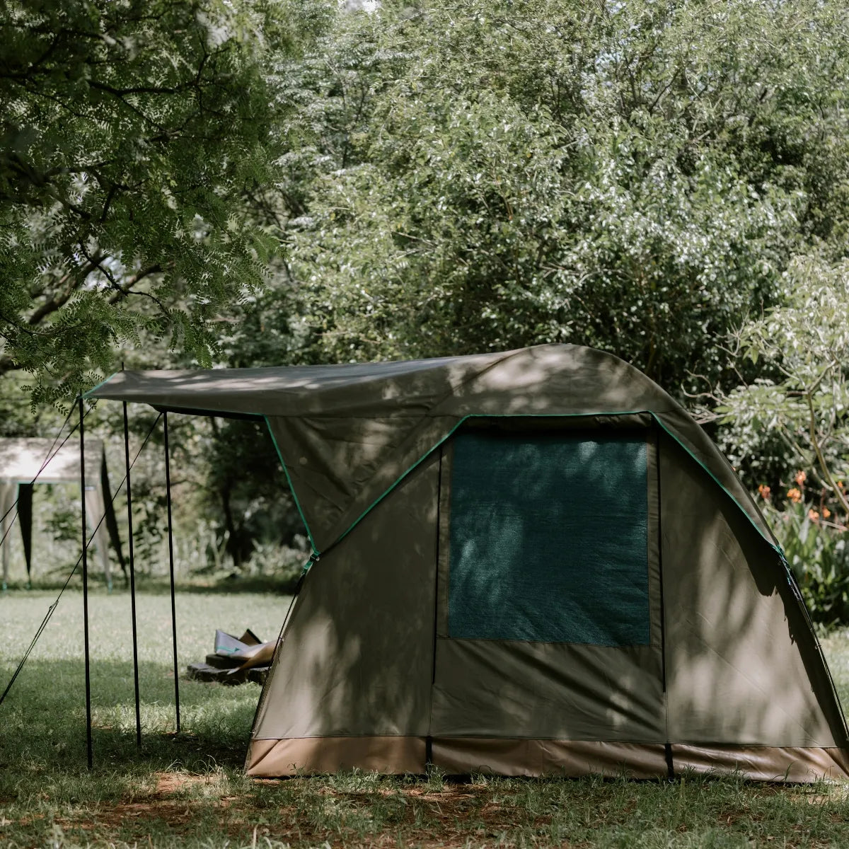 Tent set up in a grassy area with trees in the background