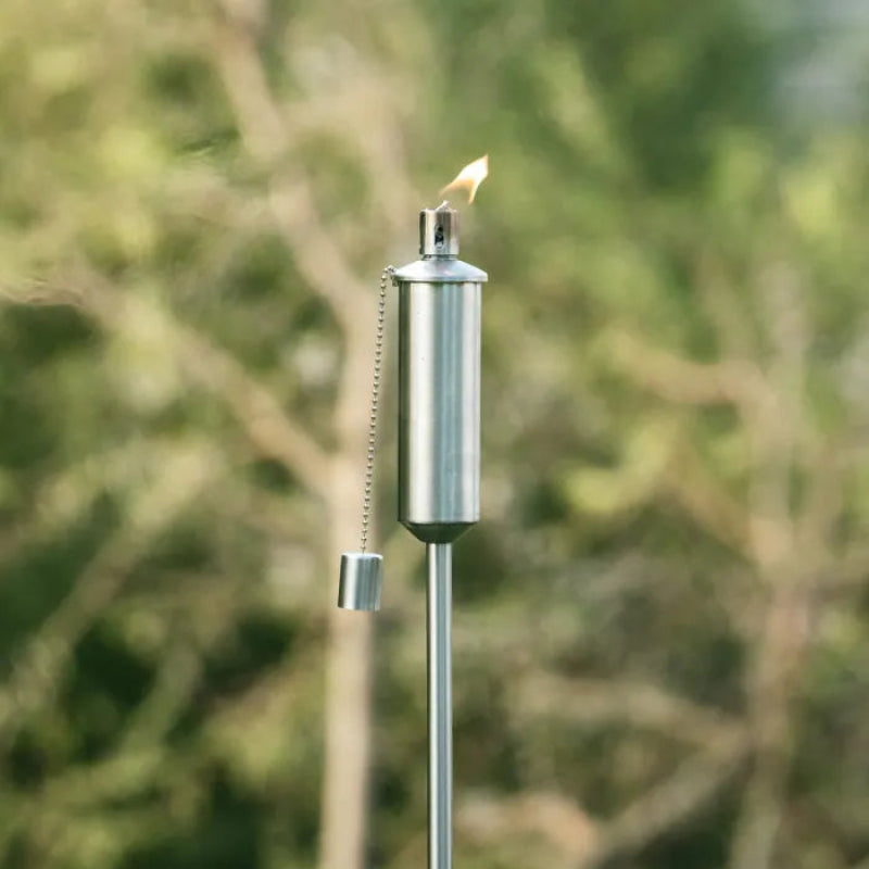 Metallic torch with flame against a blurred green background