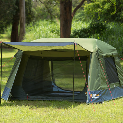 Green camping tent with a screen porch in a grassy area with trees