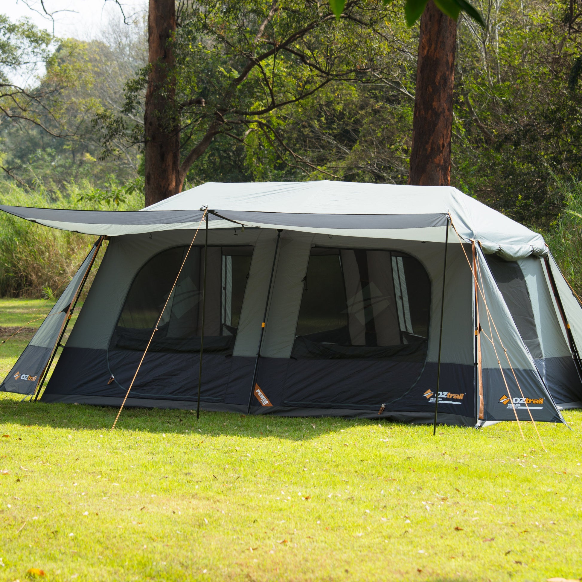 Camping tent set up on grass with trees in the background