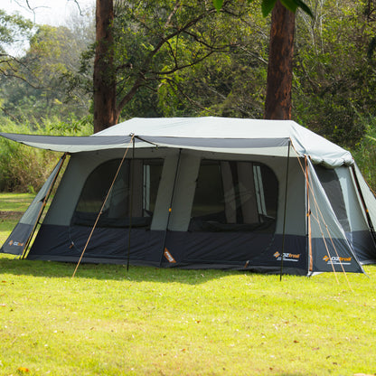 Camping tent set up on grass with trees in the background