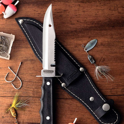 Fishing knife with sheath on a wooden surface with fishing lures and hooks.