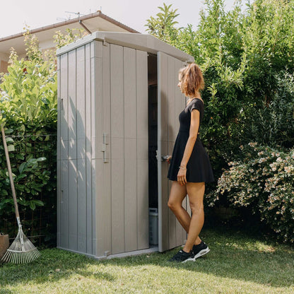 Woman standing next to a garden shed in a backyard setting