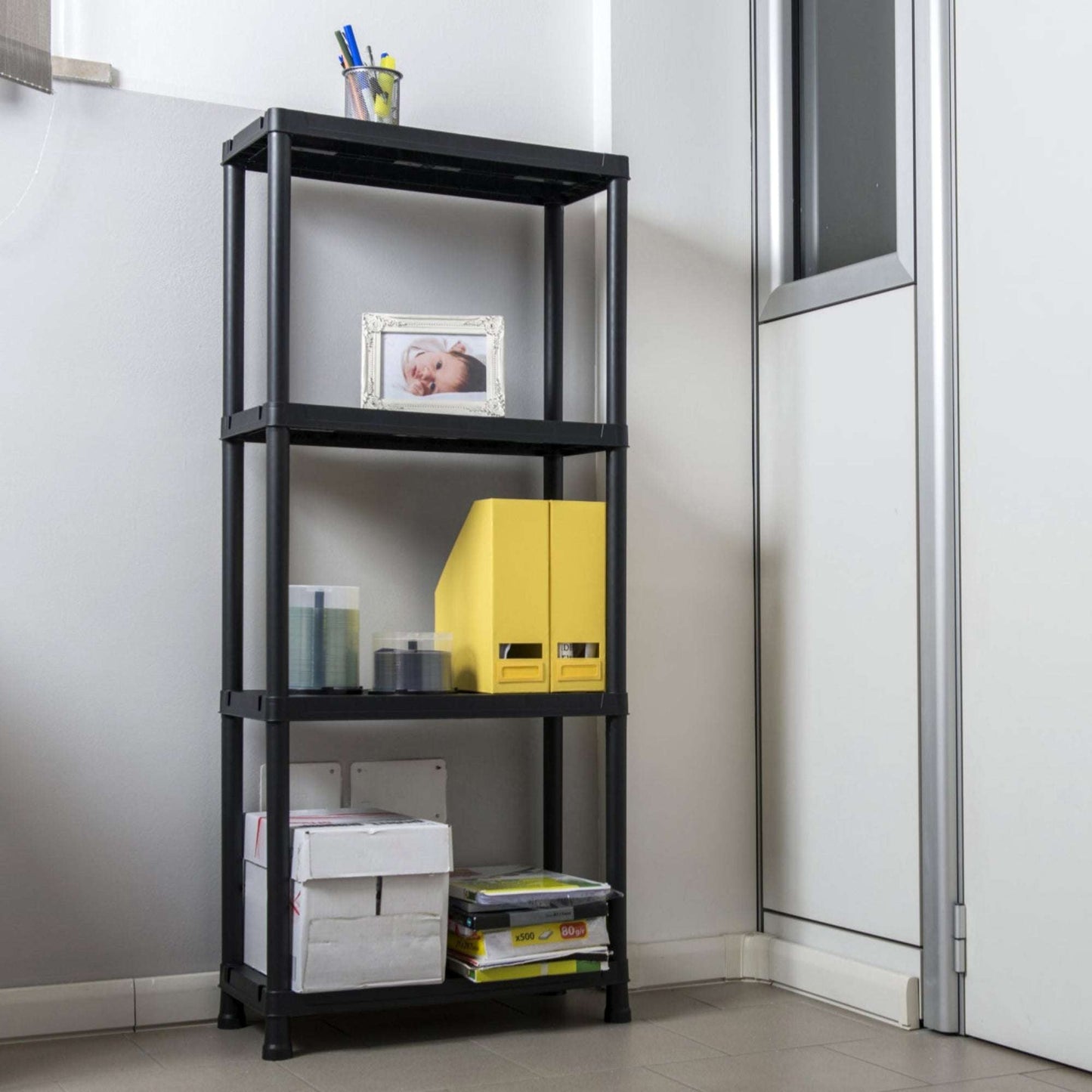 Black shelf with various items against a white wall