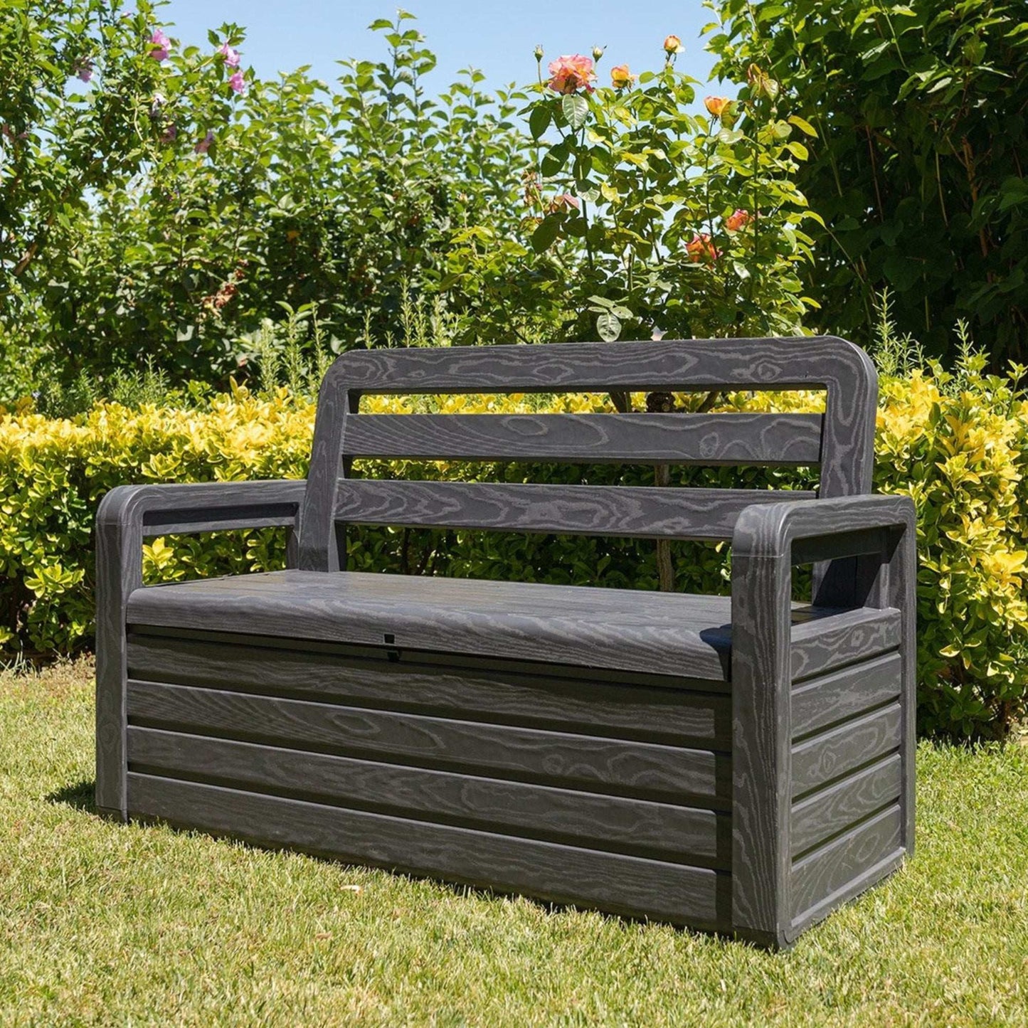Black garden bench in a grassy area with greenery in the background