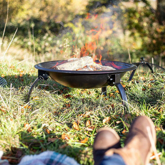 Person sitting by a portable fire pit in a grassy outdoor setting