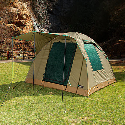 Camping tent with attached screen porch on grassy area with rocky cliff background