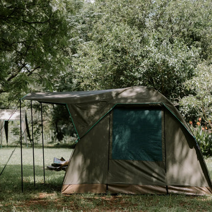 Tent set up in a grassy area with trees in the background